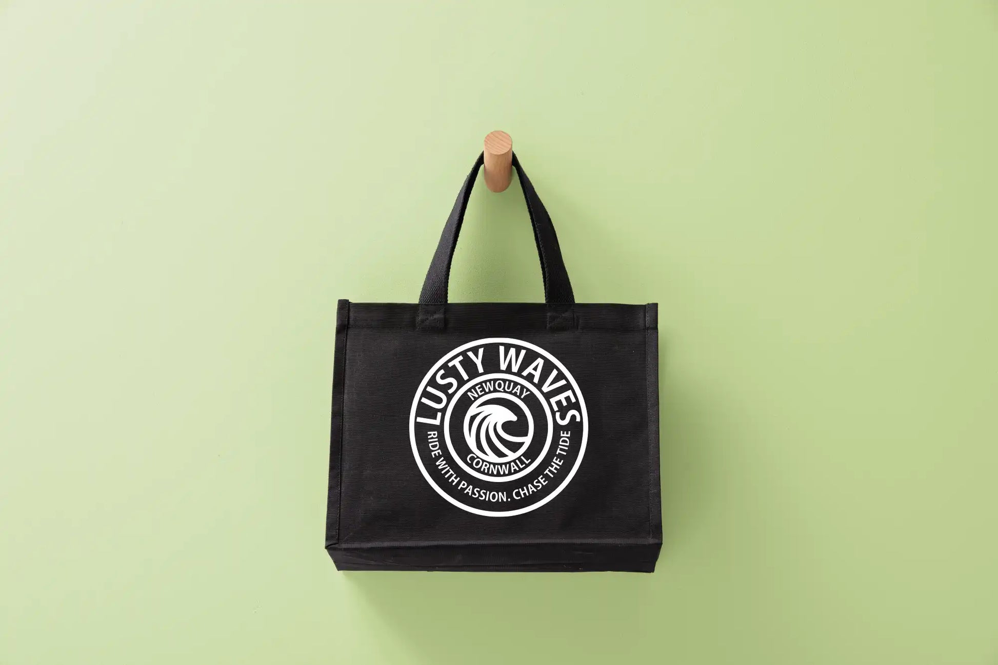 A black Lusty Waves beach bag with blue logo and text, displayed against a blue background.